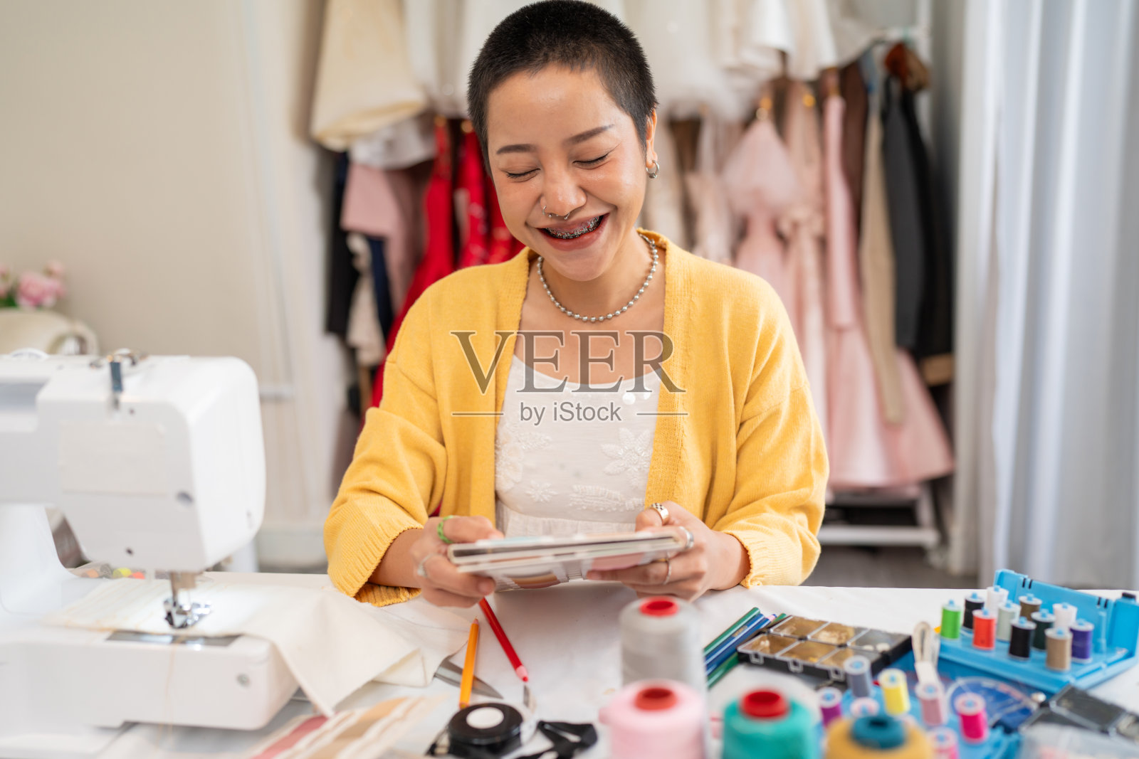 年轻女性时装设计师的肖像时尚工作在裁缝工作室。照片摄影图片