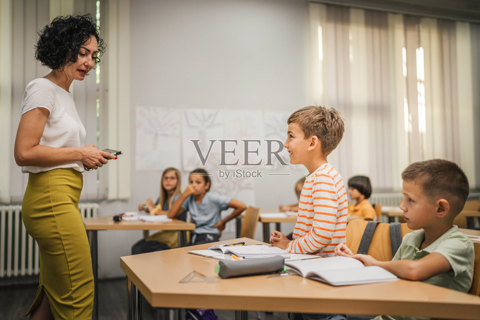 年轻的白人男孩站着回答老师的问题照片摄影图片