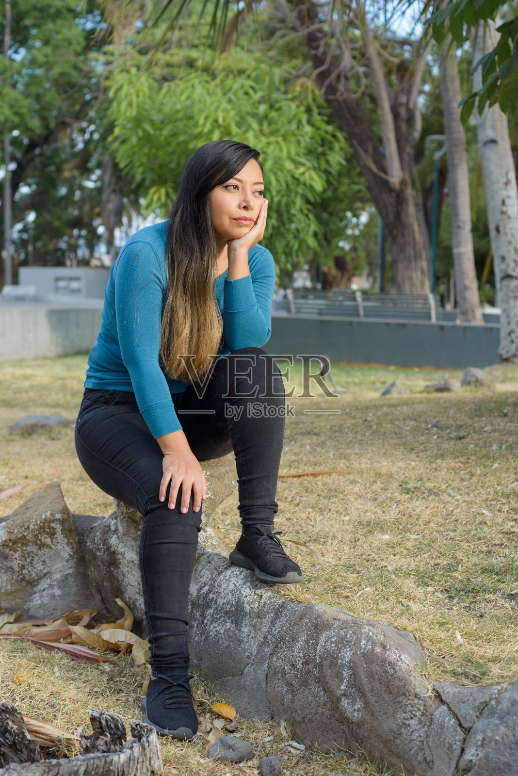 一个女人坐在公园里，一副全神贯注、若有所思的样子。照片摄影图片