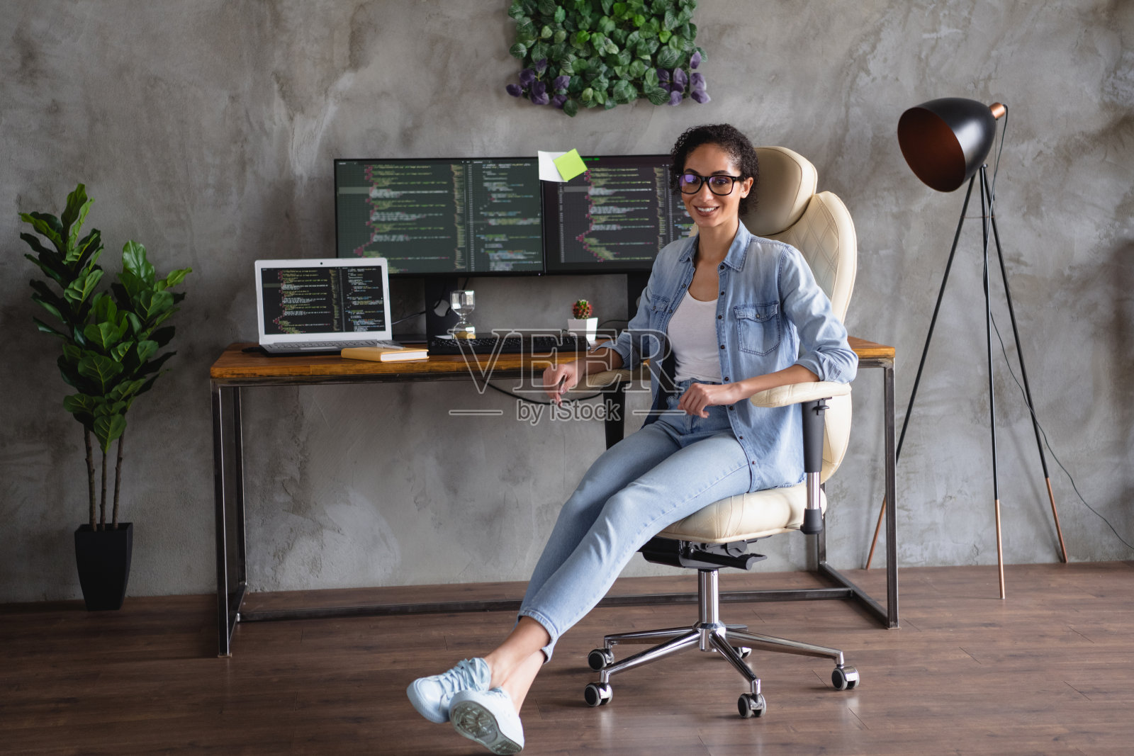 成功的迷人女孩的照片，穿着时尚的牛仔衬衫，坐在扶手椅上，用现代技术在室内工作照片摄影图片