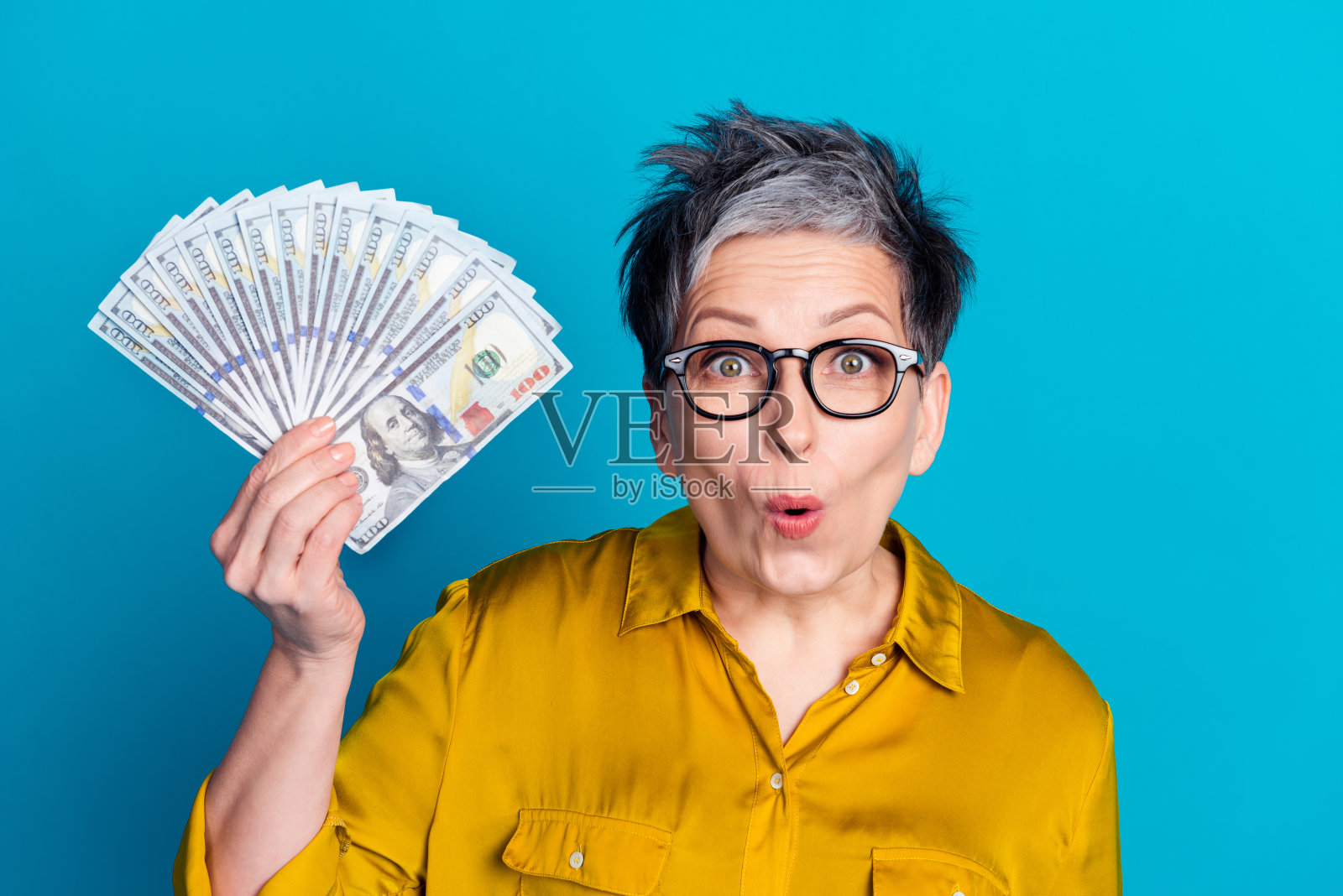 照片中开朗兴奋的女子戴罩衫眼镜微笑的手臂脸颊孤立的蓝色背景照片摄影图片