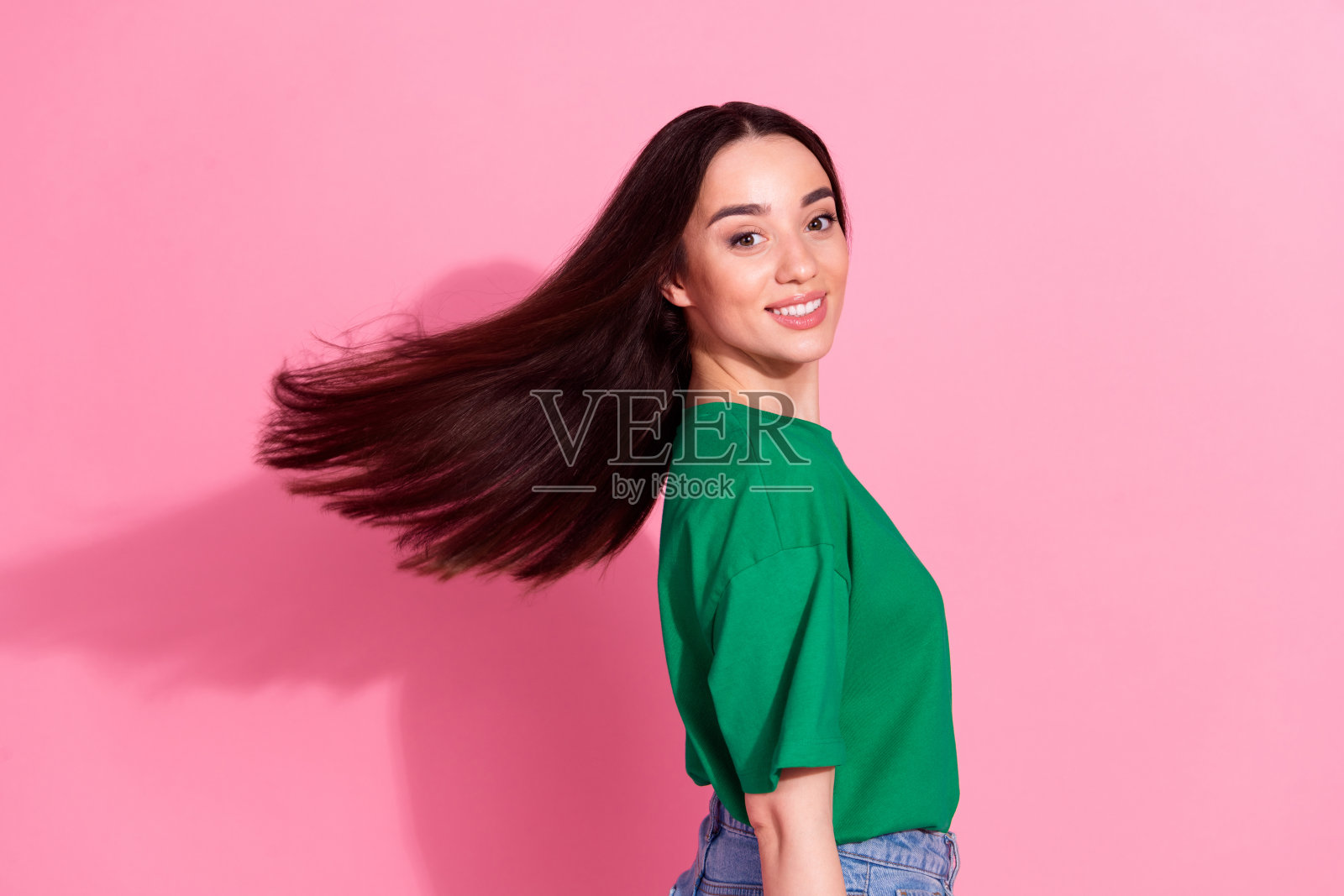照片中开朗无忧无虑的女士穿着绿色t恤微笑着，空旷的空间孤立了粉红色的背景照片摄影图片