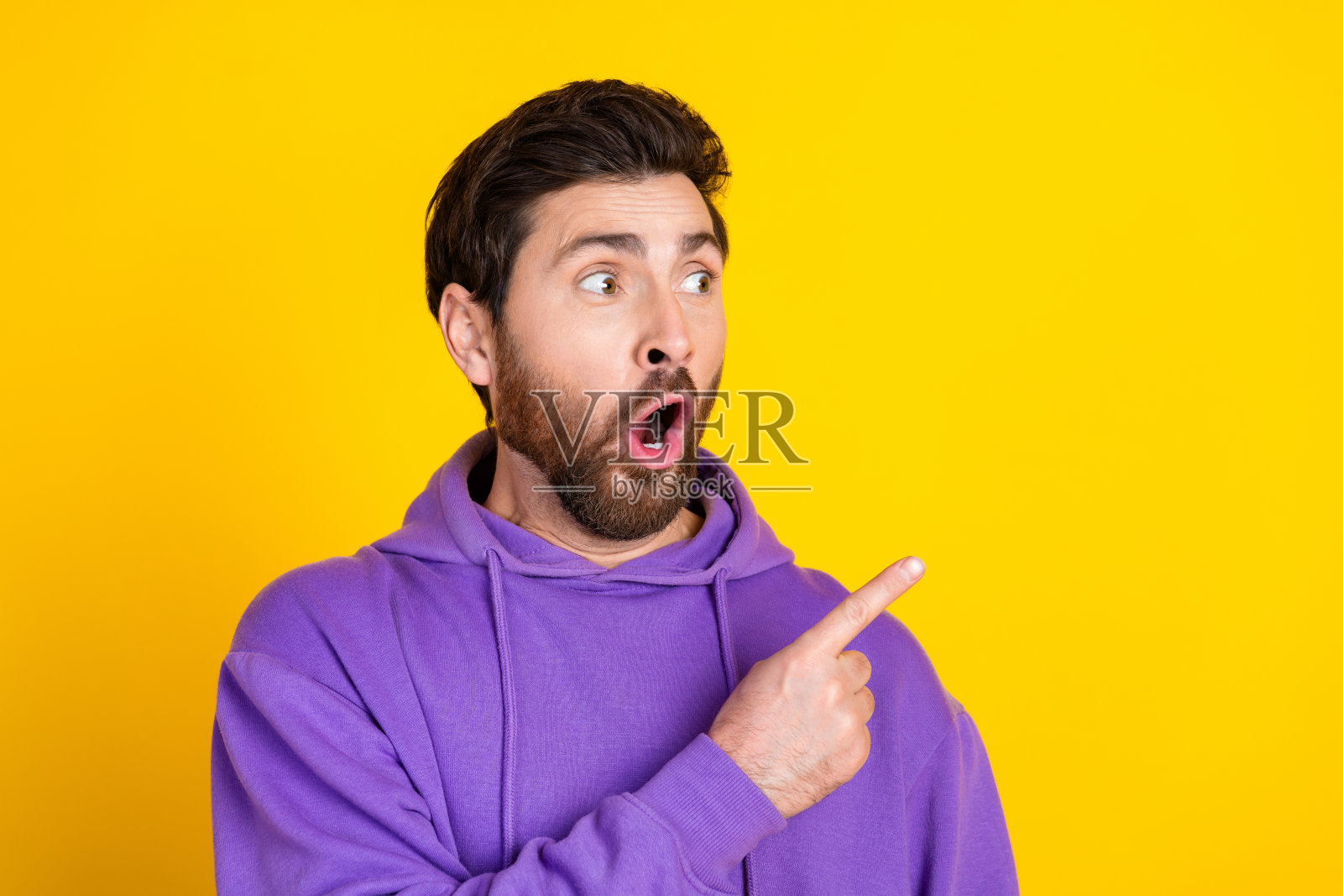 无语男子的照片，时尚的鬃毛穿着紫色卫衣，直接看着黄色背景上孤立的销售空间照片摄影图片