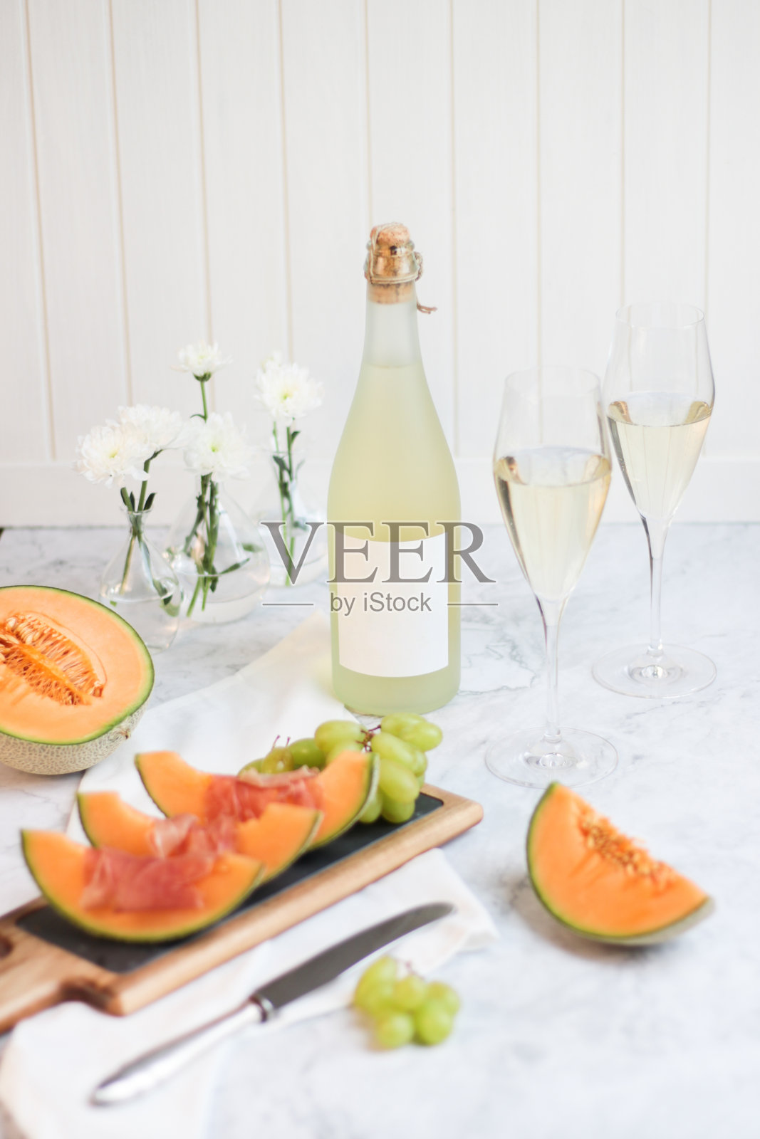 早午餐桌上的起泡酒普罗赛克香槟酒与甜瓜和塞拉诺火腿小吃开胃菜和葡萄在明亮的厨房照片摄影图片