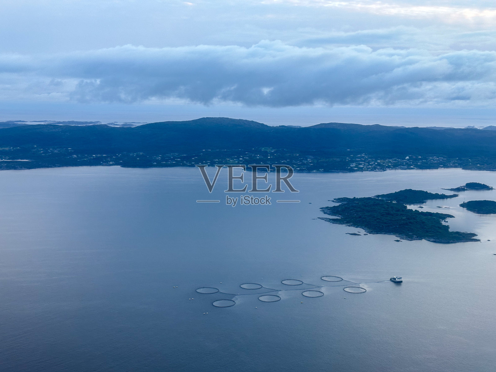 从挪威西海岸豪格森德和卑尔根之间的飞机上看到的北海沿岸峡湾的工业化鲑鱼养殖鸟瞰图照片摄影图片