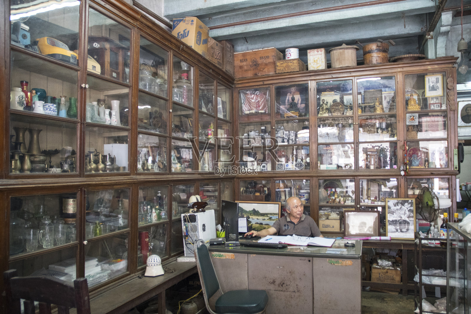 北碧府步行街的古董店老板坐在他的办公桌上照片摄影图片