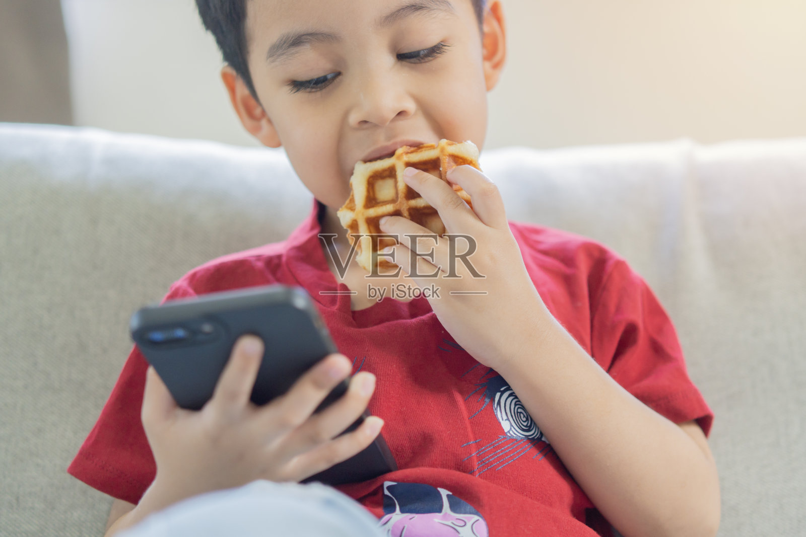 孩子在智能手机上吃东西和看动画片，因为无恐惧症照片摄影图片