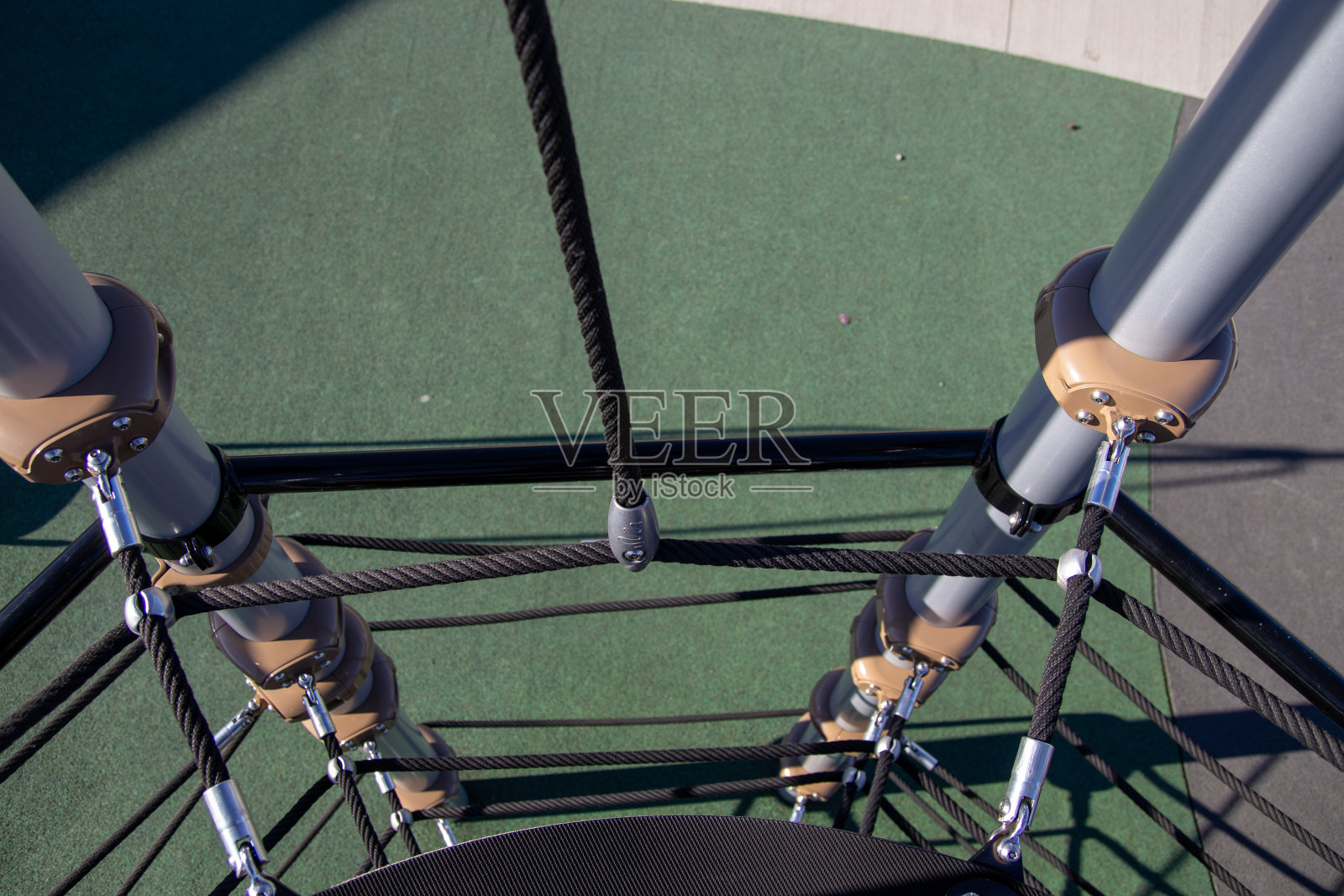 操场设备有坚固的绳索结构和坚固的金属杆-阴影投在合成草皮上照片摄影图片