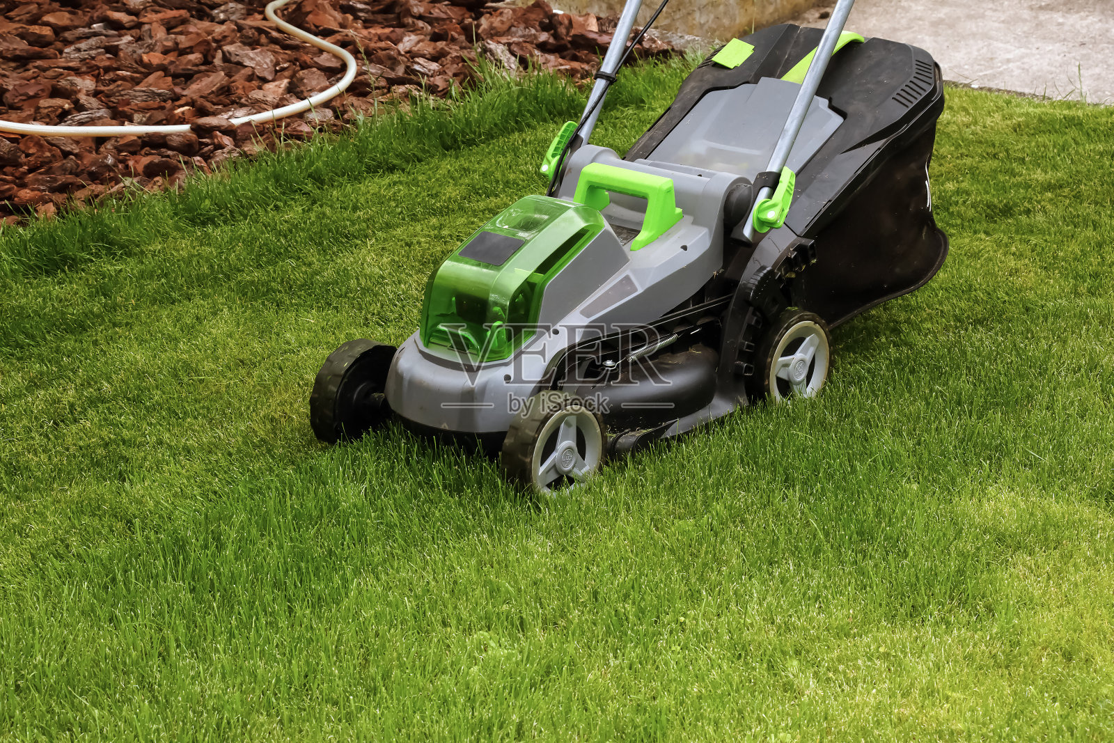 一个年轻人正在他美丽的绿色夏日花园里用割草机割草照片摄影图片