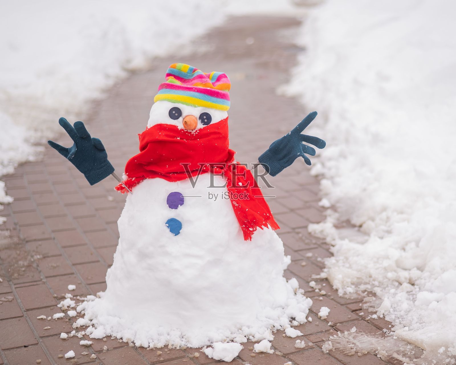 雪人戴着帽子和手套从人行道上的石板上走下来。照片摄影图片