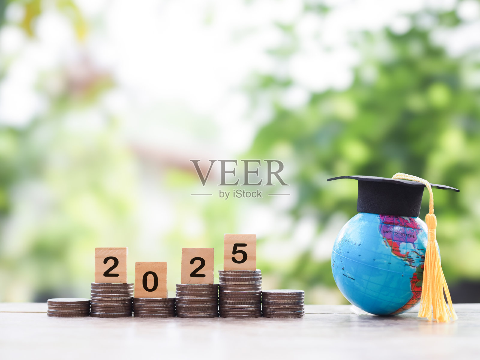 带毕业帽的地球仪，一叠硬币上刻有数字2025的木块。为2025年的教育、学生贷款、奖学金、学费存钱的概念。照片摄影图片