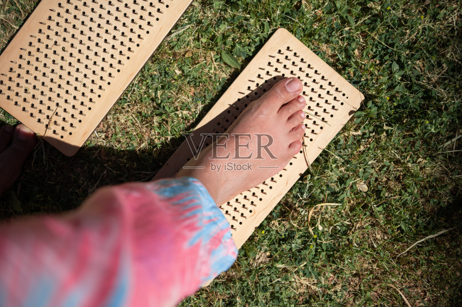 一个人在草地上用木制的足部按摩板练习反射疗法的特写照片摄影图片