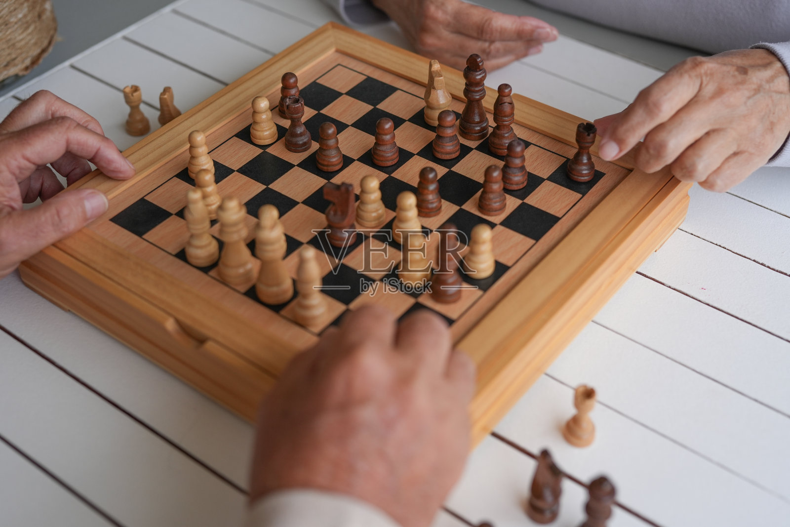 近距离的棋盘和老年夫妇的手下棋的人在家里的木桌上。退休后的休闲生活方式、策略及解决问题的方法照片摄影图片