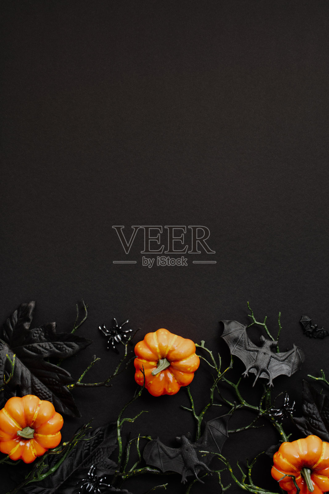 以万圣节为主题的背景，有充满活力的迷你南瓜，深色的叶子，还有蝙蝠和蜘蛛等令人毛骨悚然的装饰。完美的季节性促销和平面设计。照片摄影图片