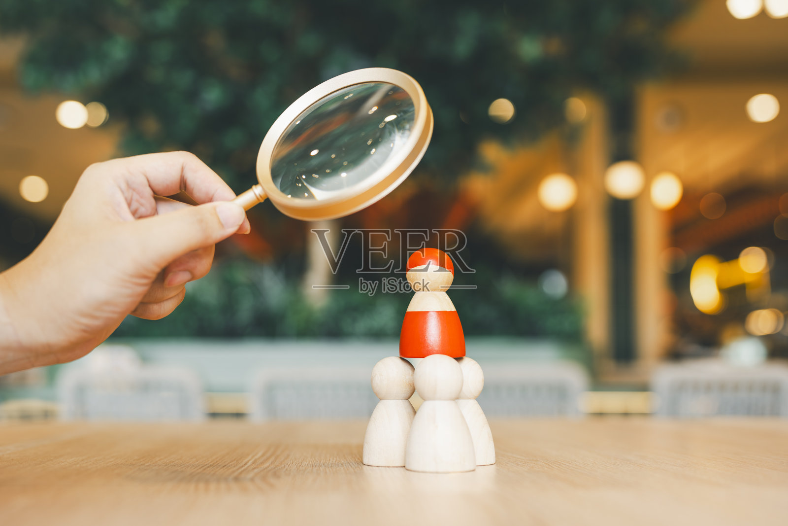 一个放大镜和一个红色木头人模糊的商人寻找一个特别的人。人力资源管理和招聘的概念。照片摄影图片