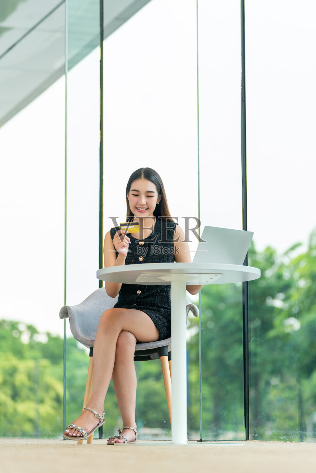 年轻女子在现代咖啡馆用笔记本电脑和信用卡网上购物照片摄影图片