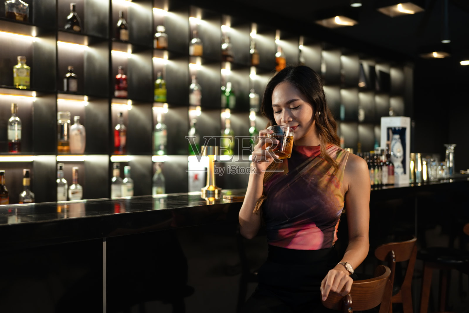美丽的年轻女子在城市的夜总会享受着一杯威士忌照片摄影图片