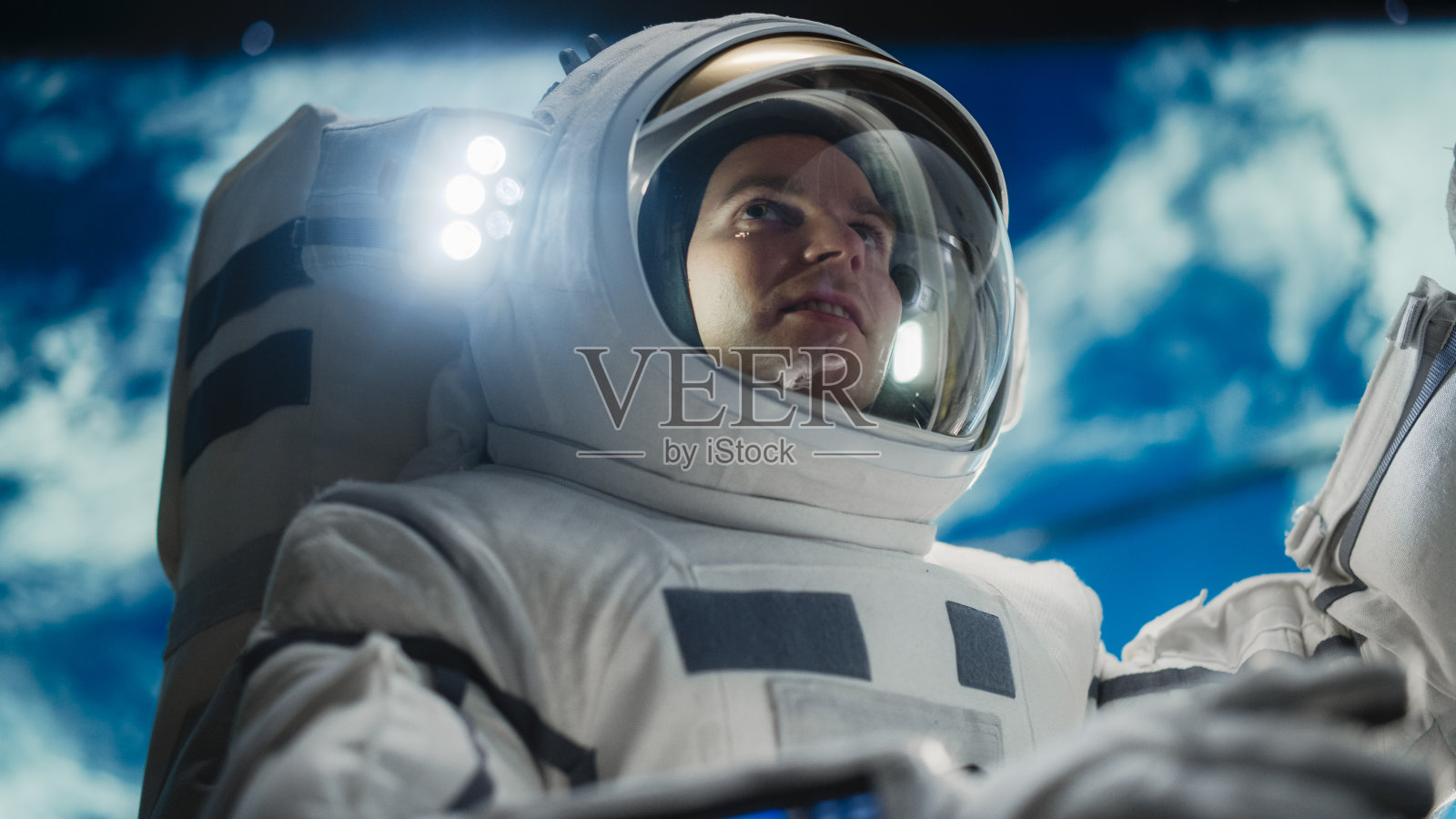 一位英俊的年轻宇航员在外太空调查卫星的肖像。身着太空服在先进航天器外执行舱外活动的训练有素的专业人员照片摄影图片