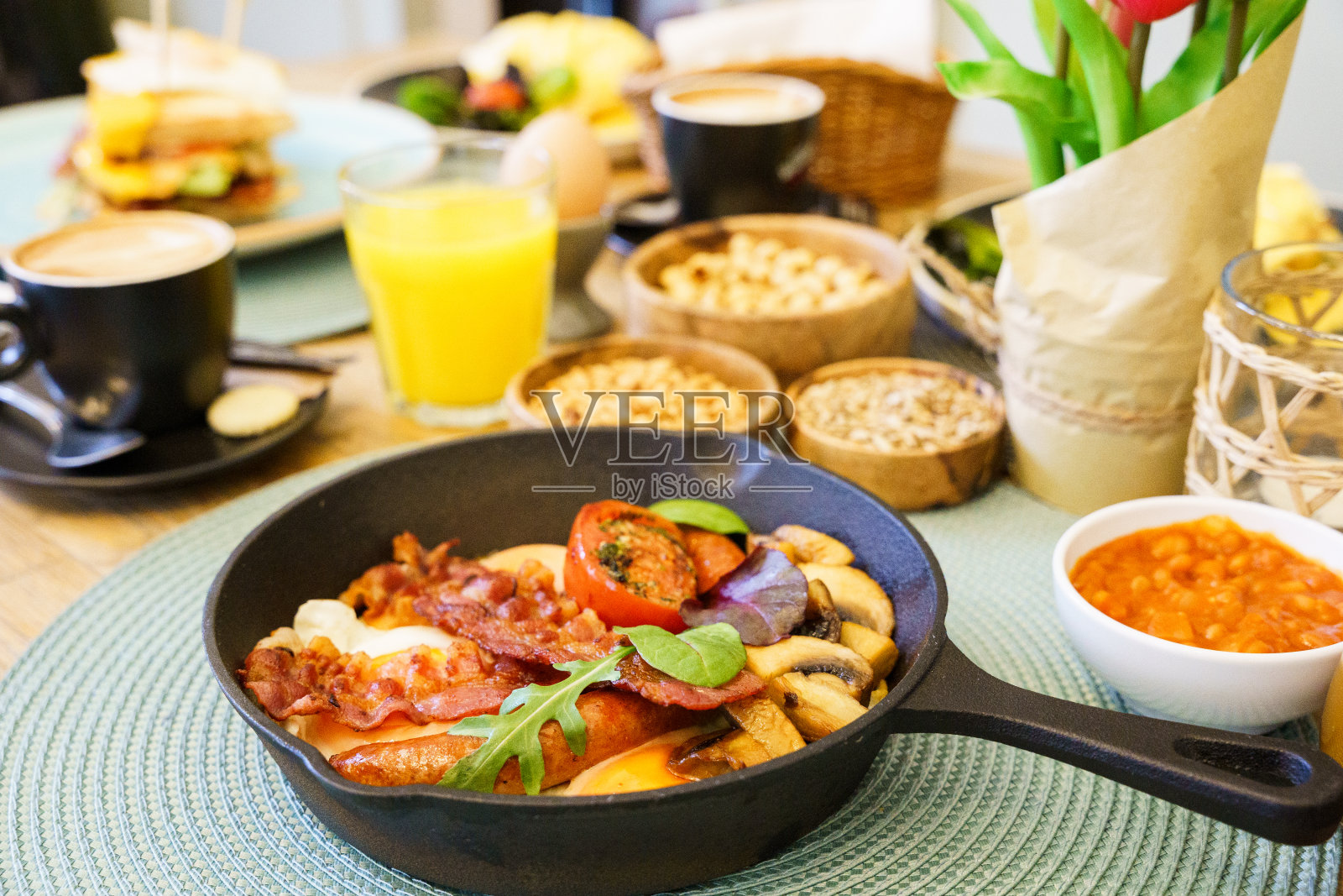 英式早餐用煎锅煎鸡蛋、香肠、熏肉、蘑菇、豆子和西红柿照片摄影图片