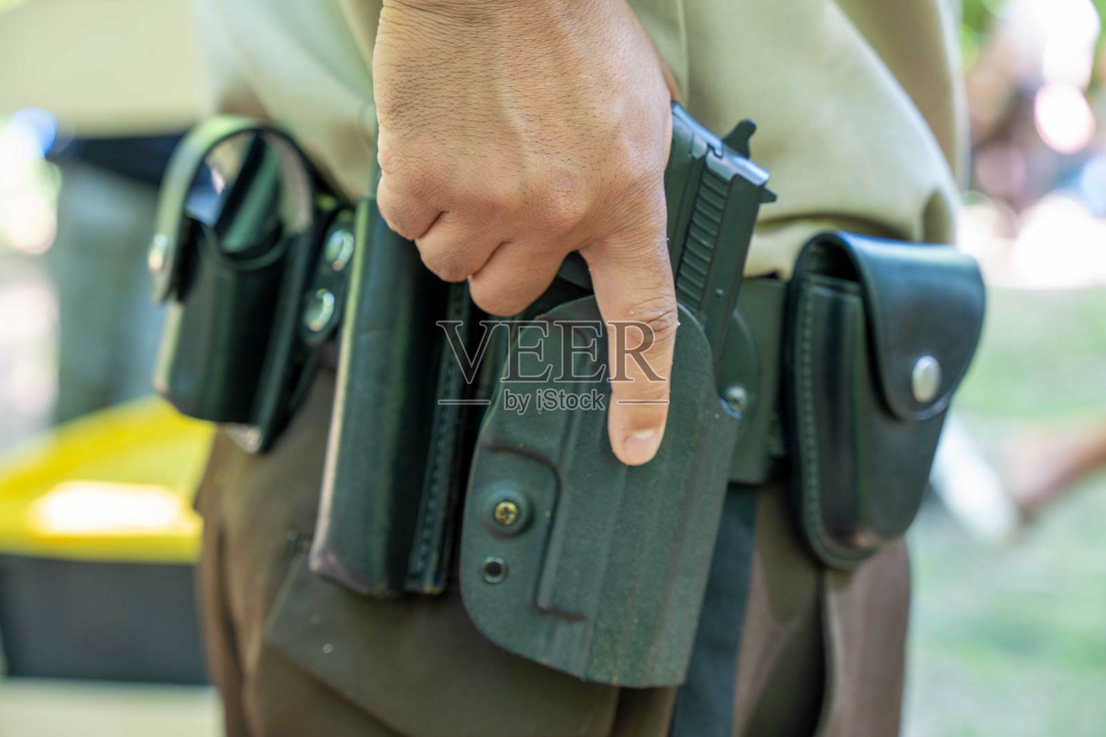 近距离拍摄警察的手和枪套。照片摄影图片