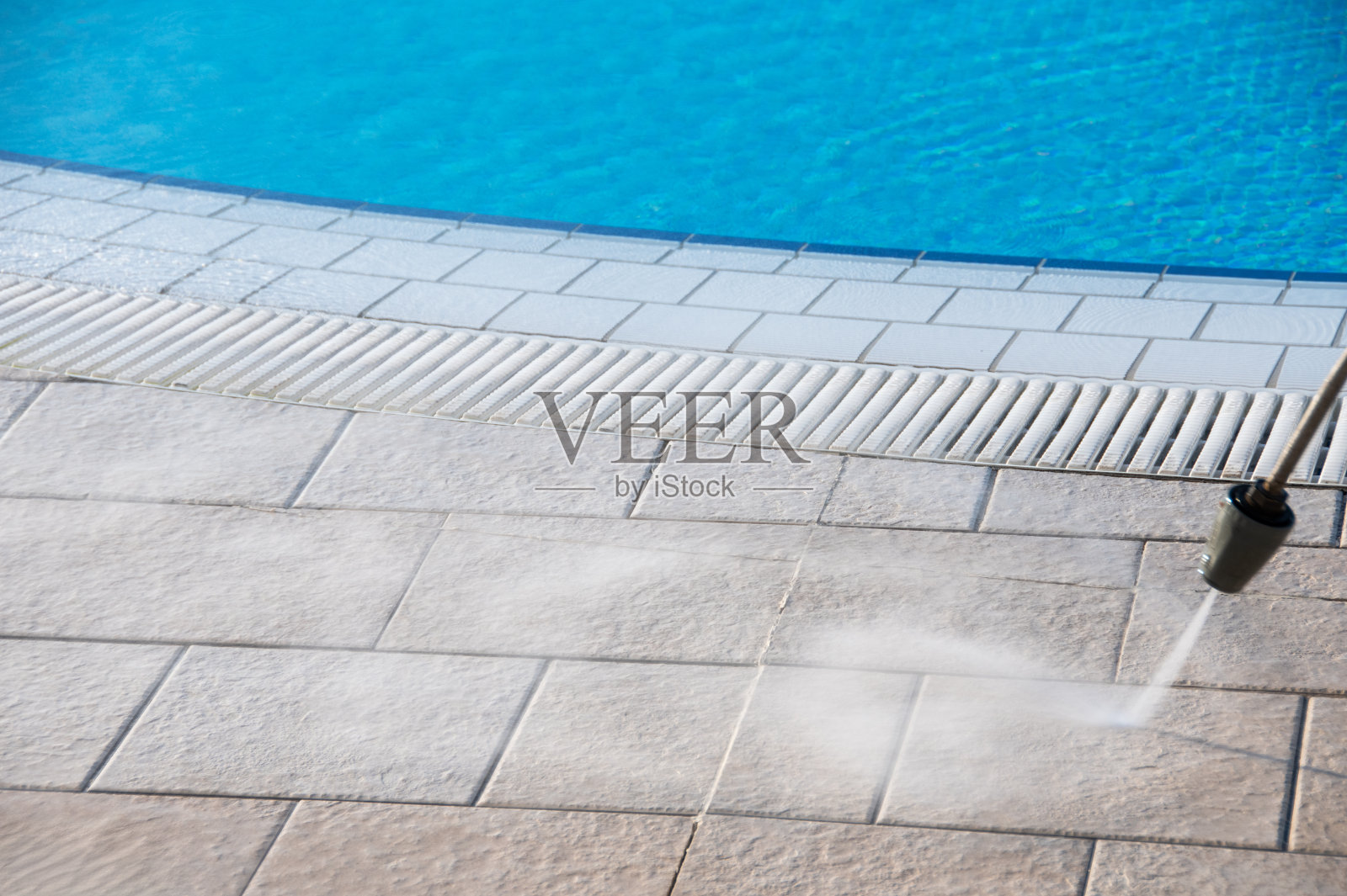 清爽夏季泳池清洁高压水射流，蓝色的水，明亮的晴天，泳池边缘特写照片摄影图片