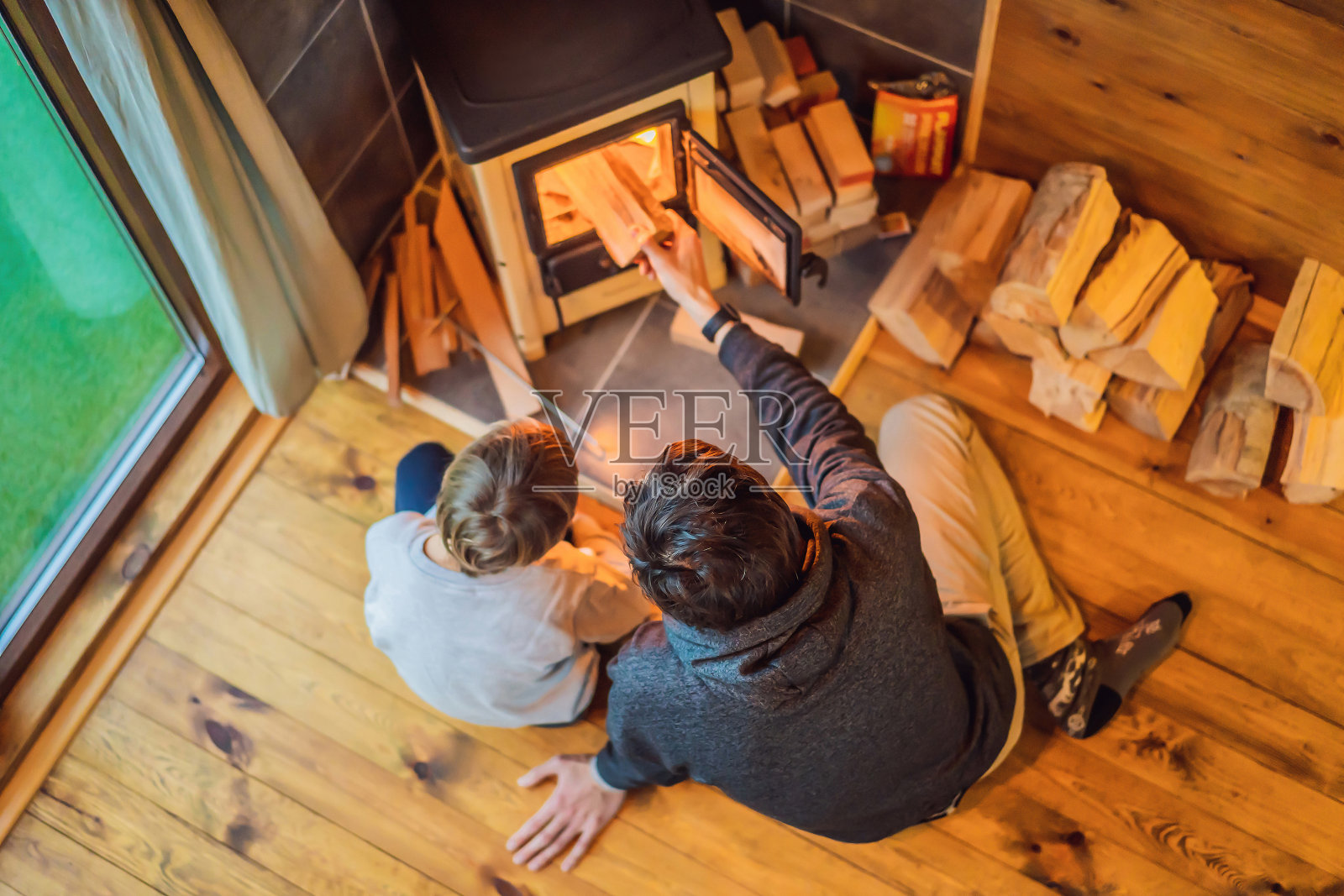 父亲和儿子在豪华野营的壁炉旁消磨时光。在Glamping的山上休息。山间小屋里舒适的壁炉照片摄影图片