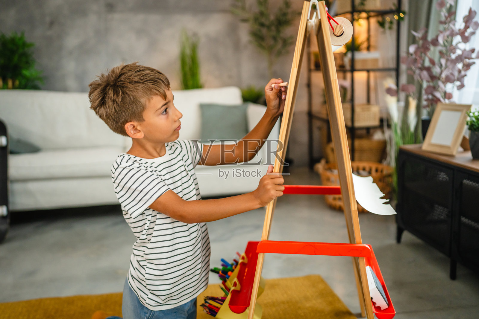 小男孩在客厅用白粉笔在黑板上画画照片摄影图片