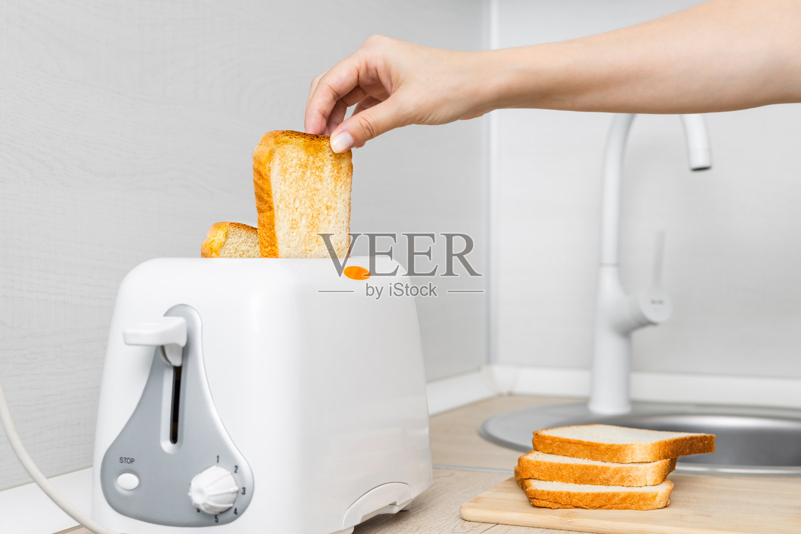 手从烤面包机里拿出烤面包，特写。照片摄影图片