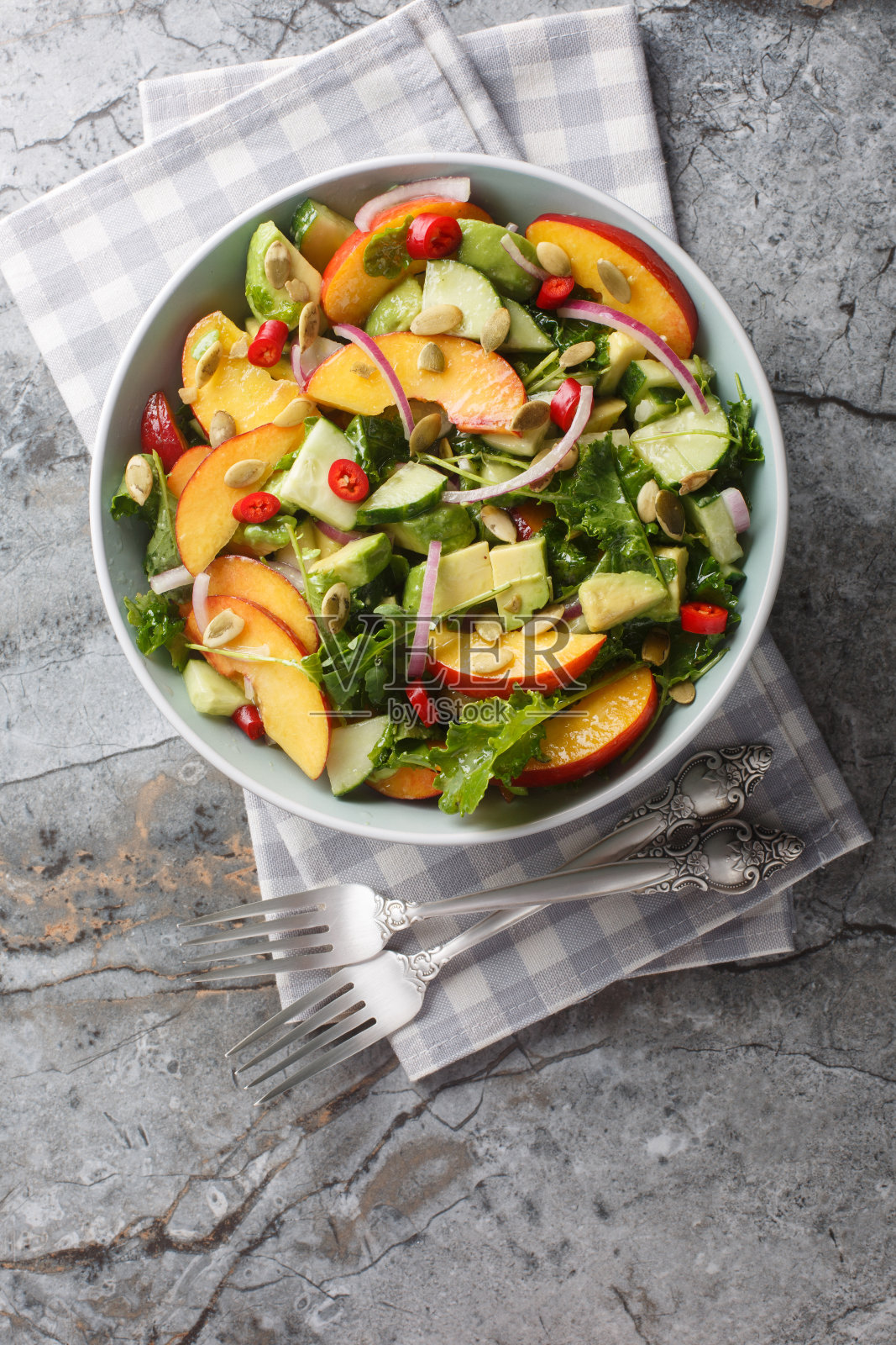 素食水蜜桃牛油果沙拉，配以红洋葱、辣椒、芝麻菜、菠菜和南瓜子，配以橄榄油。垂直俯视图照片摄影图片