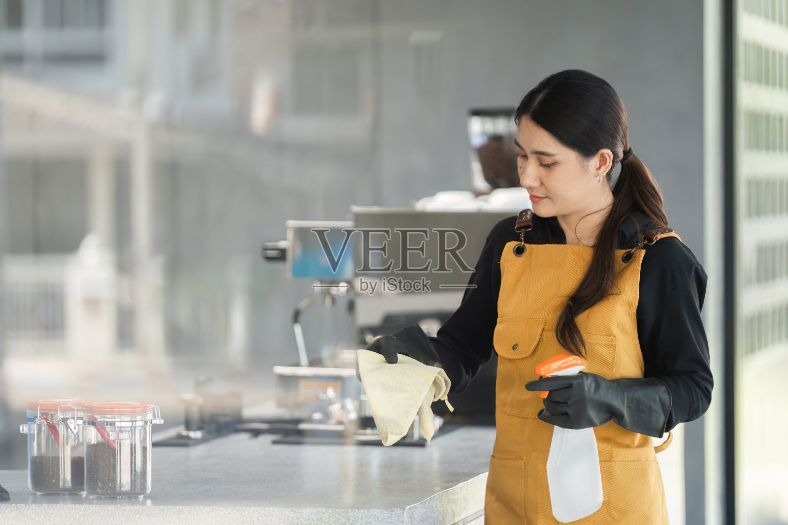 女员工在现代咖啡馆用喷雾瓶和布清洁咖啡厅柜台照片摄影图片