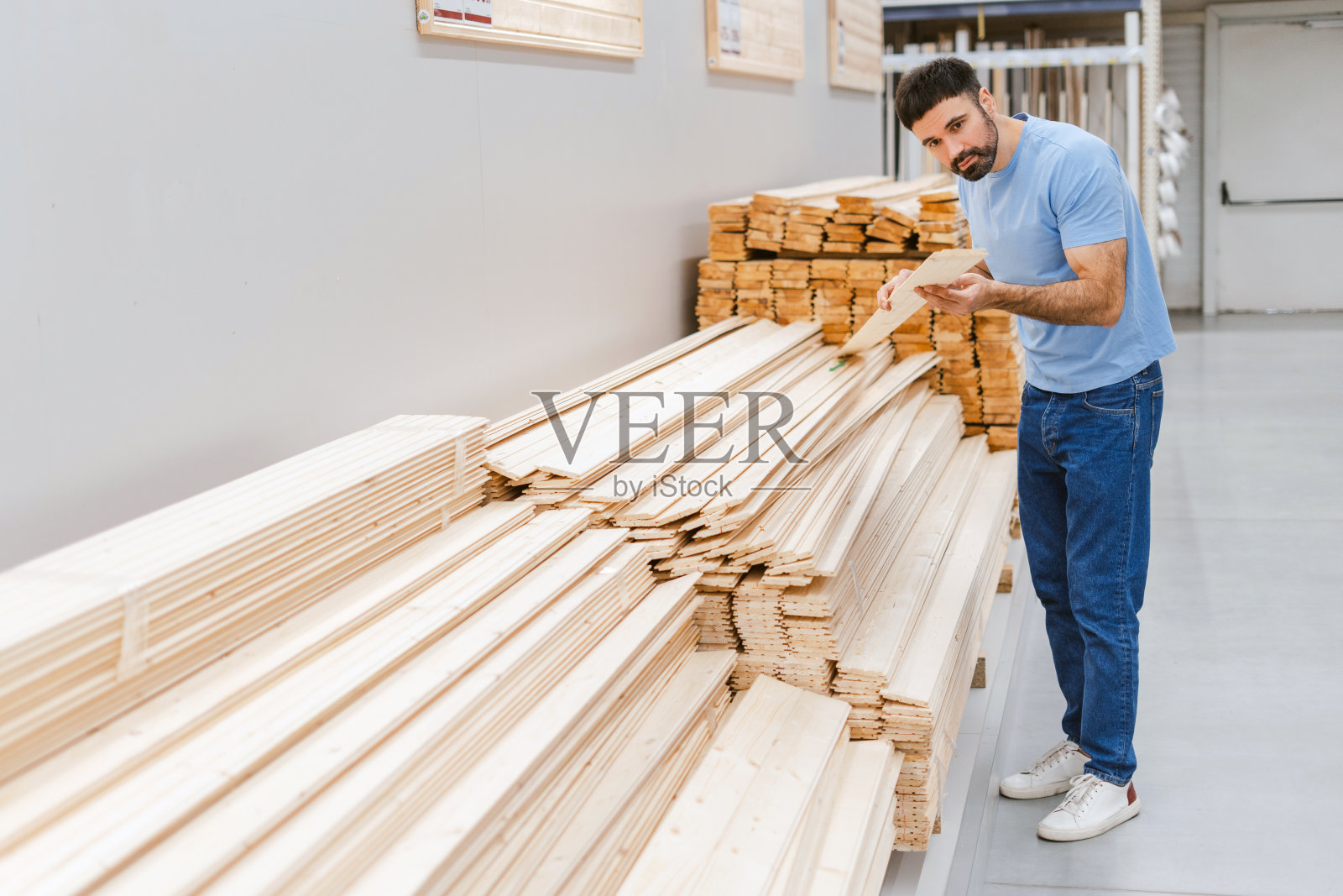 一名男子在建筑超市里挑选胶合板和木板照片摄影图片