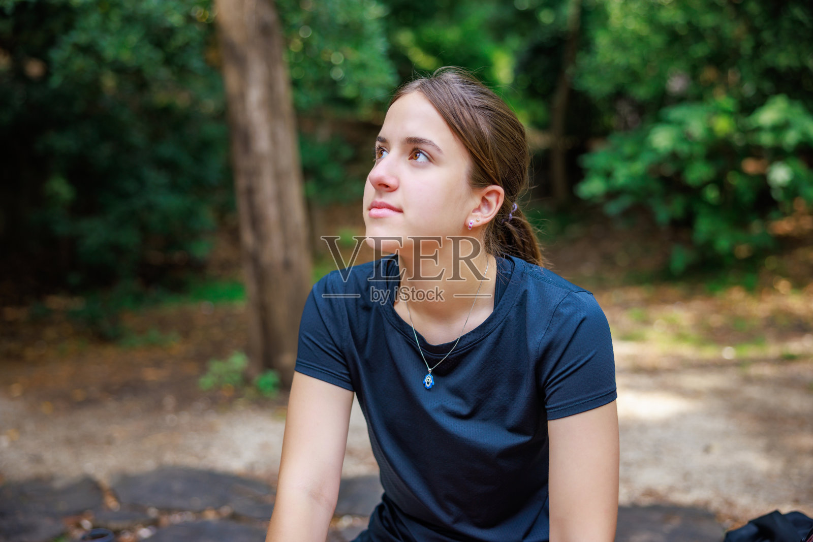 夏天，穿着t恤的美丽少女在自然公园里降温的肖像照片摄影图片