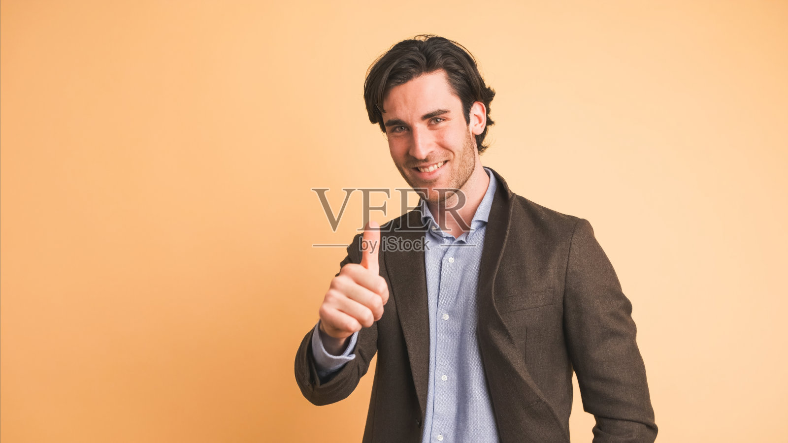 快乐的商人在棕色工作室竖起大拇指照片摄影图片