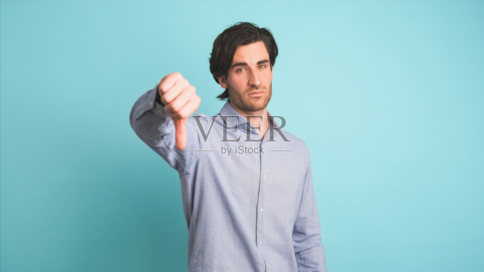 沮丧的男人在蓝色画室里拇指朝下照片摄影图片