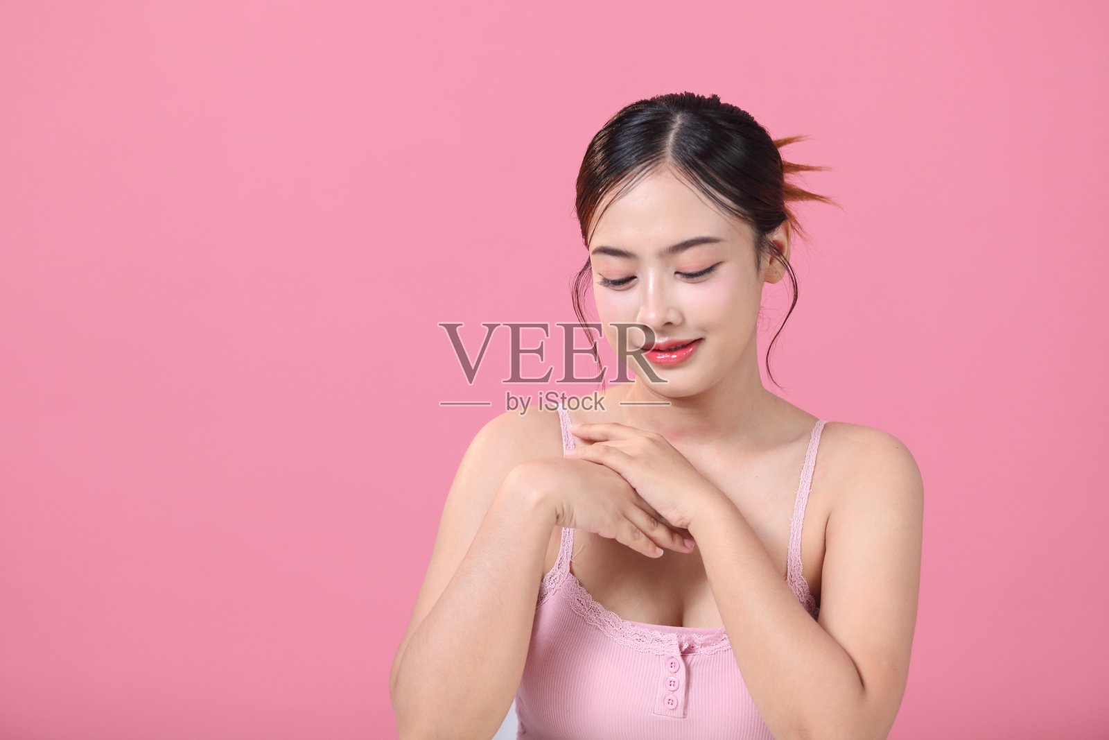 美丽的年轻亚洲女人干净新鲜的皮肤在粉红色的背景，面部和皮肤护理照片摄影图片