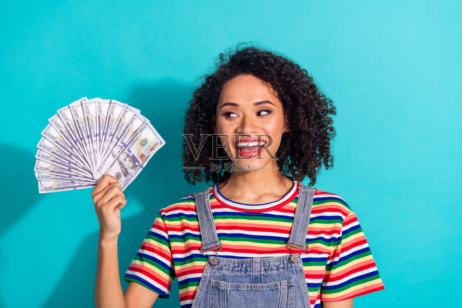 照片正面的女孩拿着钱扇看起来孤立的蓝色背景照片摄影图片