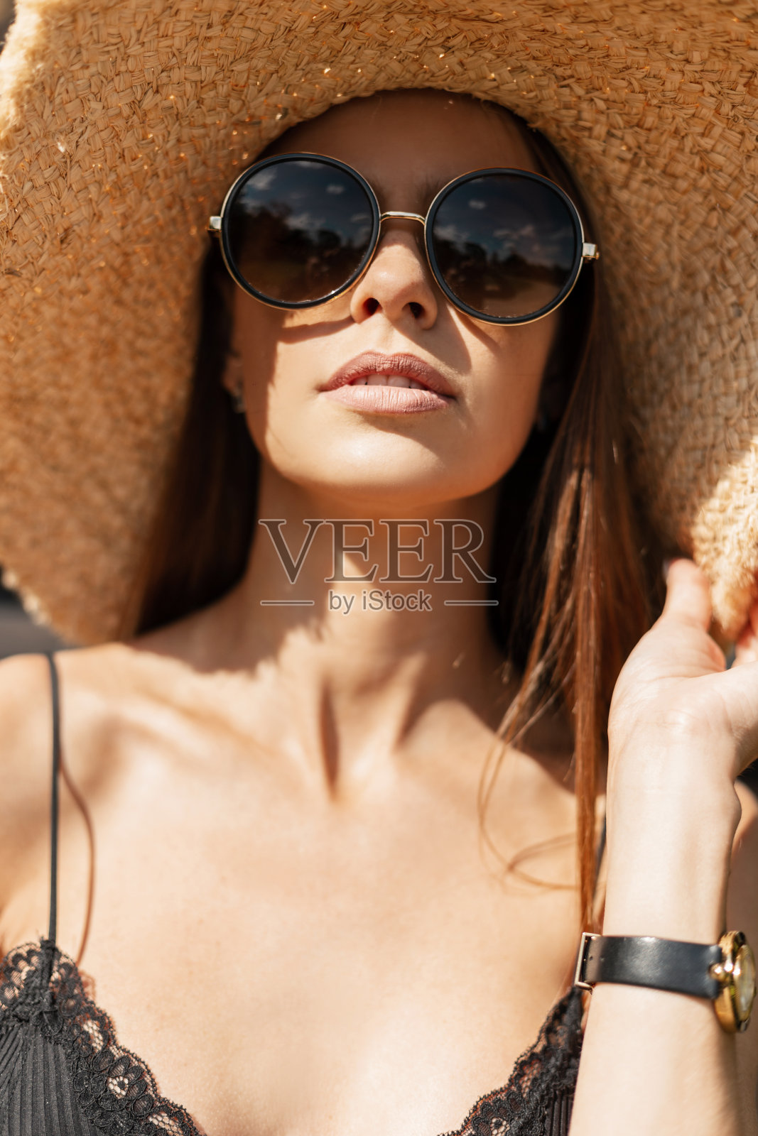 凉爽的夏季肖像美丽的时尚年轻女子在时尚草帽与复古圆形太阳镜在海滩上照片摄影图片