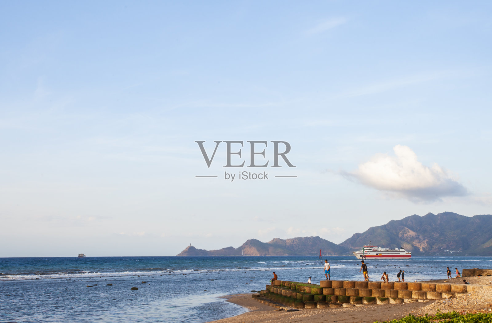 在东帝汶帝力市的卡拉帕海滩，人们在沙滩上锻炼身体，欣赏日落。从这个海滩上，也可以从远处看到Tanjung Fatucama的Cristo Rei雕像。照片摄影图片