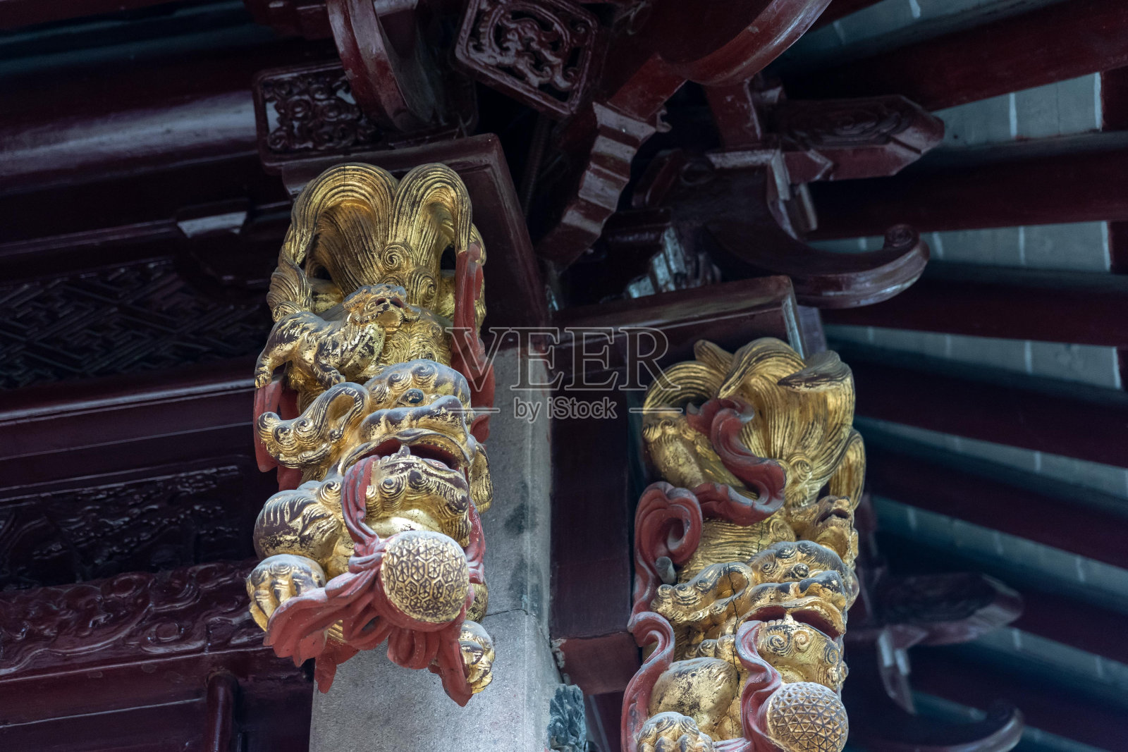 上海豫园一座中国传统亭子的木柱上装饰着错综复杂的金色和红色雕刻。照片摄影图片