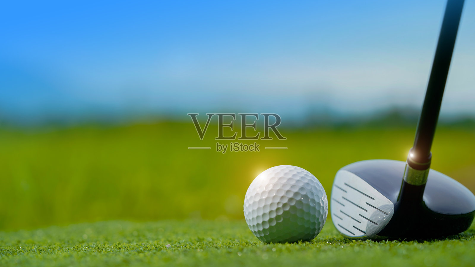 高尔夫球杆和高尔夫球在绿色的草坪在一个美丽的高尔夫球场与早晨的阳光。照片摄影图片