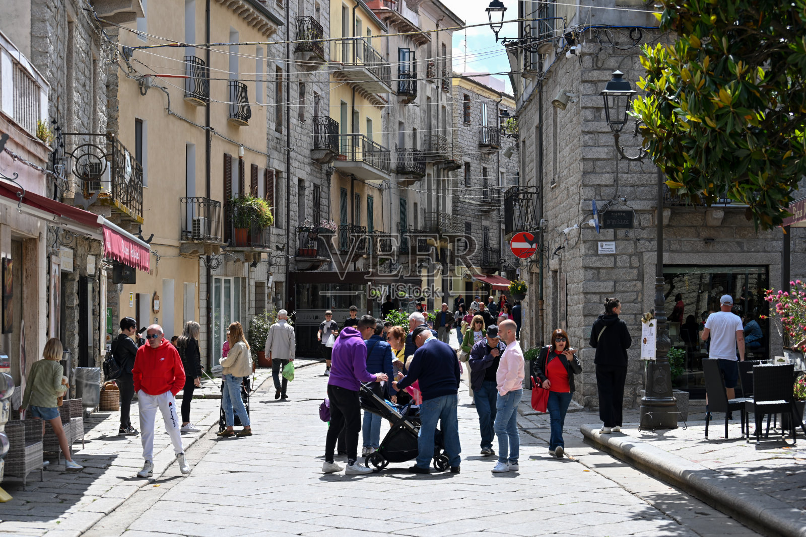 游客和当地人漫步在撒丁岛历史古城坦皮奥·保萨尼亚的罗马大道上。照片摄影图片