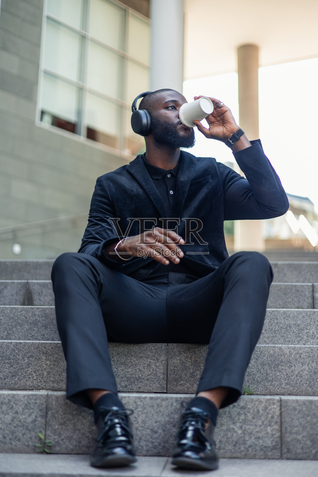 直立的非洲裔美国商人喜欢在工作休息时在楼梯上享用外卖咖啡和音乐照片摄影图片