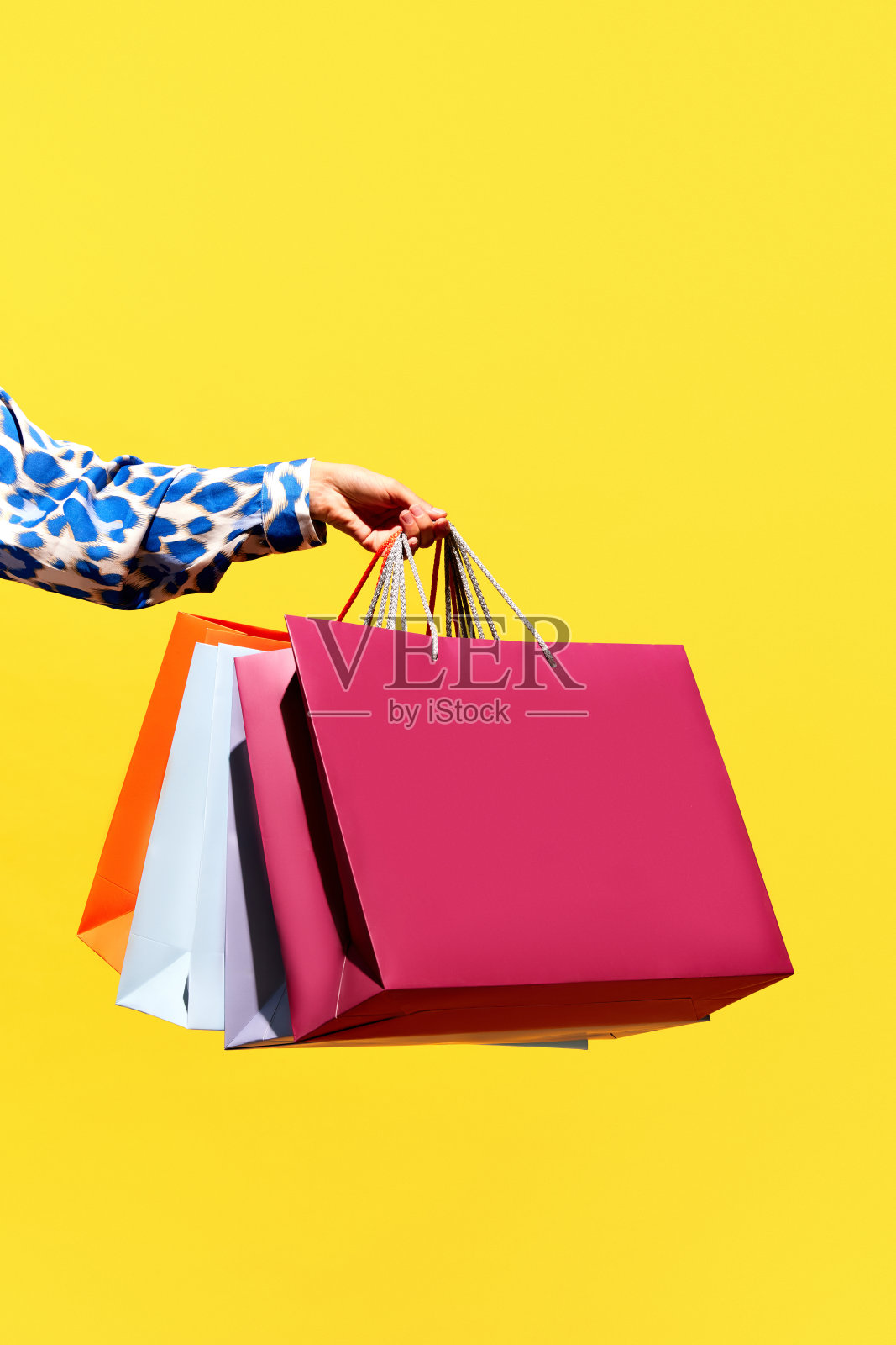 销售报价。“黑色星期五”。购物折扣。特写女士的手拿着购买彩色袋孤立在明亮的黄色背景。照片摄影图片