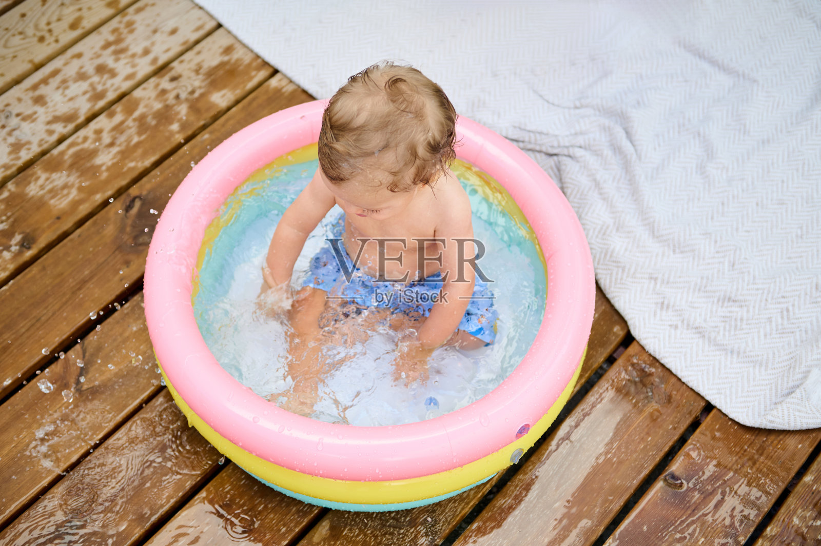 阳光明媚的日子里，快乐的小孩在充气泳池里戏水照片摄影图片