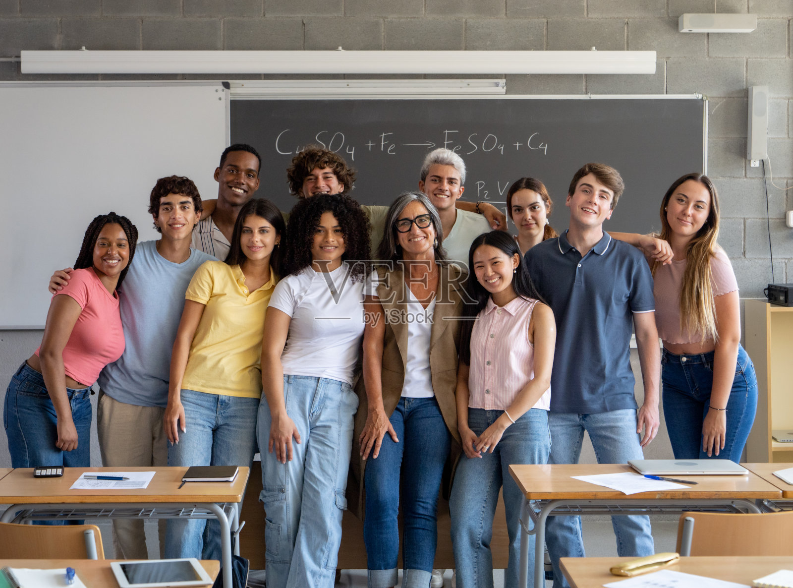 一群不同的青少年学生和一名女老师在课堂上微笑着看着镜头的肖像。高中，学年，大学照片摄影图片