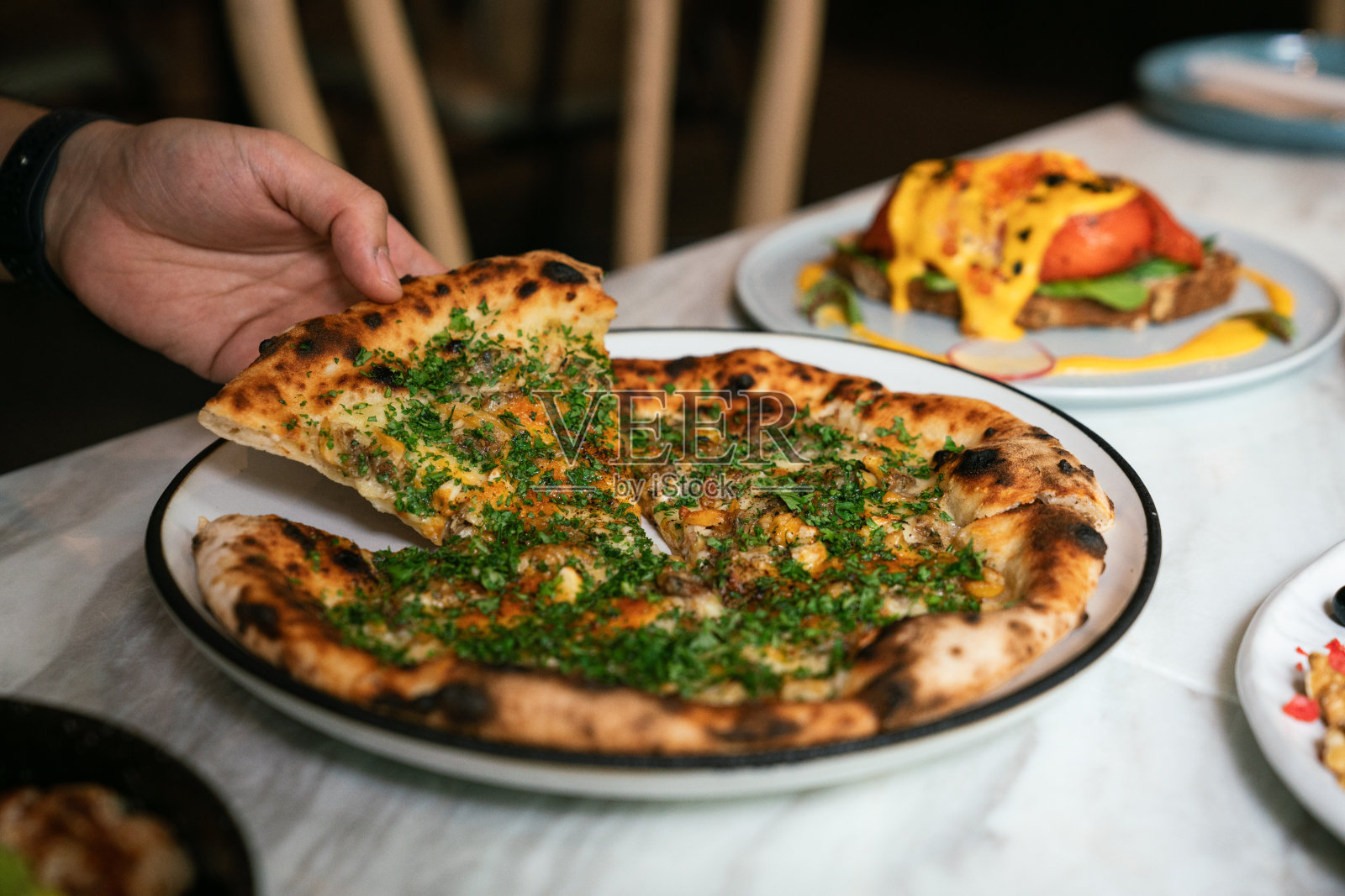 手拿披萨片。餐厅的午餐时间。食物和餐桌餐的概念。照片摄影图片