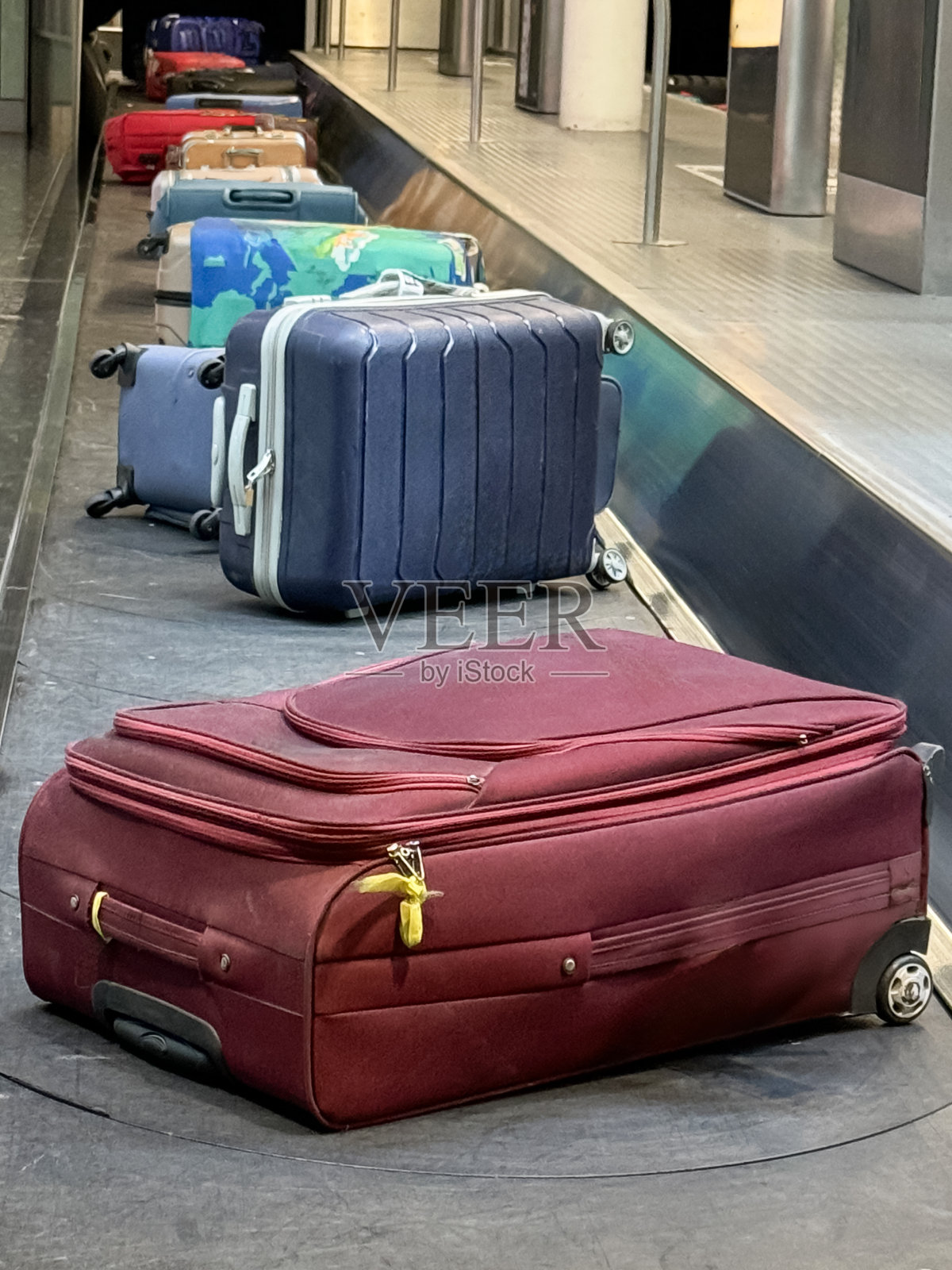 机场单层行李传送带上的轮式行李特写图像，行李认领传送带，带拉链和轮子的行李箱，重点放在前景，旅行概念照片摄影图片