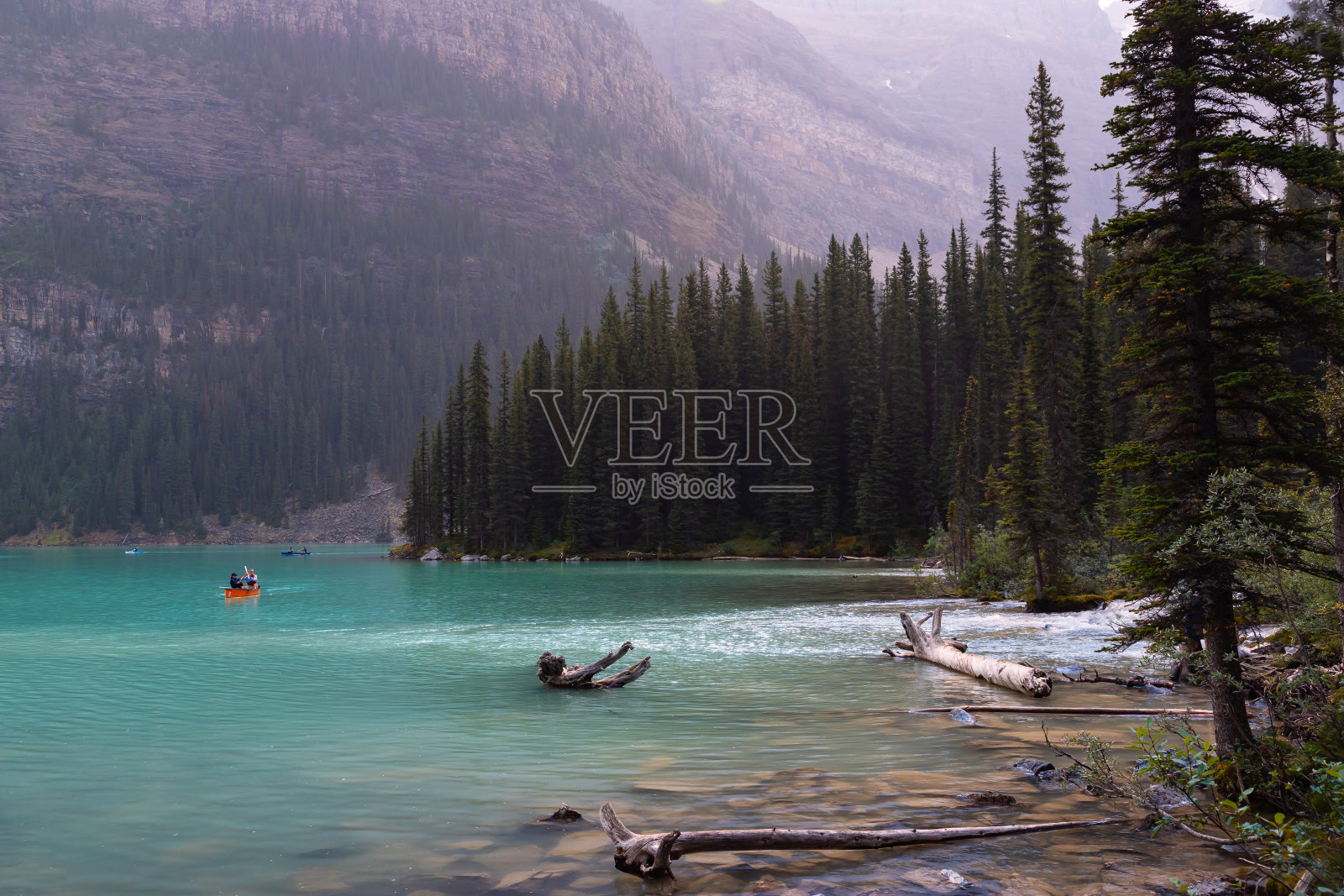 在班夫梦莲湖的红船水镜中划独木舟的划桨者照片摄影图片