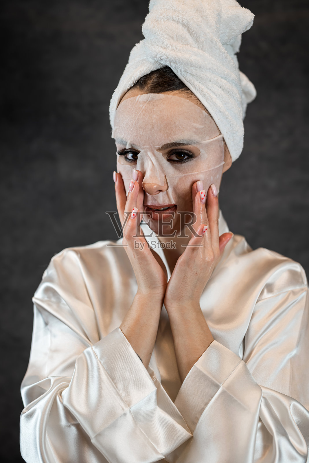 女士戴上白色毛巾敷上布片美容面膜，清洁护理面部皮肤隔离于黑色照片摄影图片