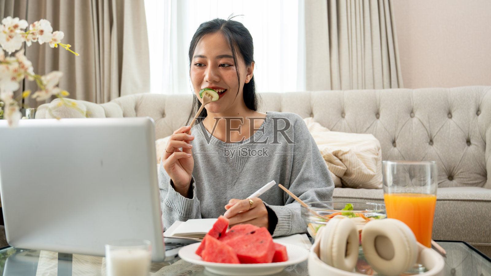 一位女士一边吃早餐，一边在咖啡桌上用笔记本电脑工作或在线学习。照片摄影图片